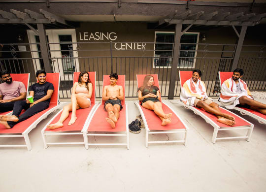 a group lounging on the pool chairs together