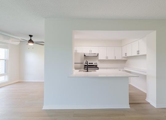 A white kitchen with a fan on the ceiling.