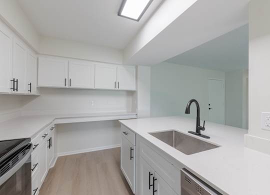 A kitchen with white cabinets and a stainless steel sink.