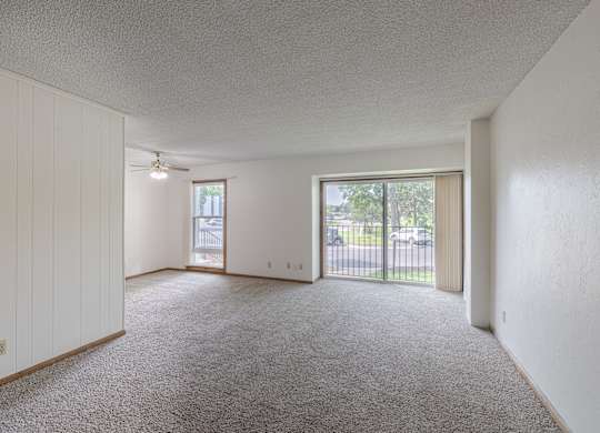 A spacious room with a carpeted floor and sliding glass doors.