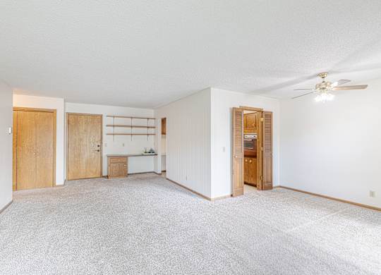 A spacious room with a ceiling fan and a white carpet.
