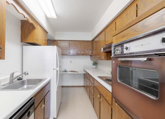 A kitchen with brown cabinets and white appliances.
