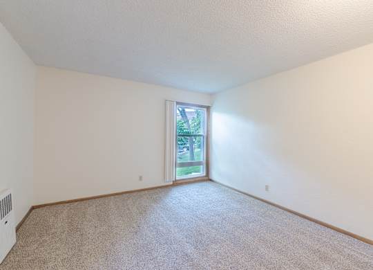 A room with a carpeted floor and a sliding glass door leading to a backyard.