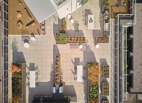 A top-down view of a courtyard with tables, chairs, and planters.