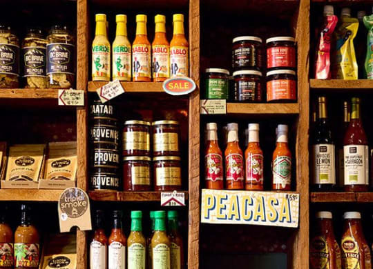 a shelf filled with different bottles of hot sauce and other drinks