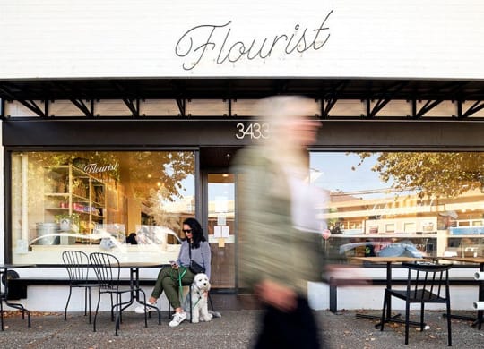 a woman sitting outside a restaurant with her dog