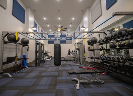 a view of the two story Wynnwood Vinings fitness center with weights and a punching bag in the middle of the room