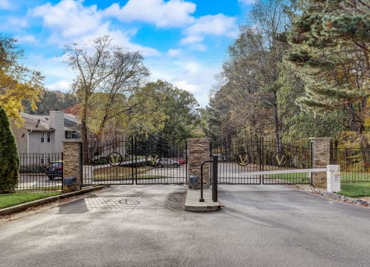 the gate at the end of a driveway with a house behind it