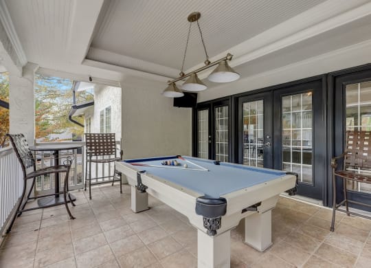 a pool table in the porch of a house with a patio