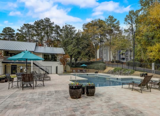 a resort swimming pool with lounge chairs and fall trees at Veridian at Sandy Springs