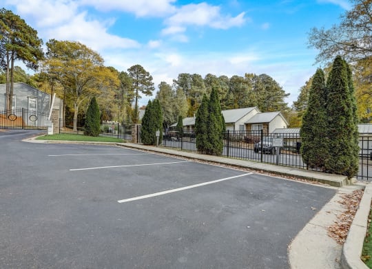 a parking lot with a fence and houses in the background