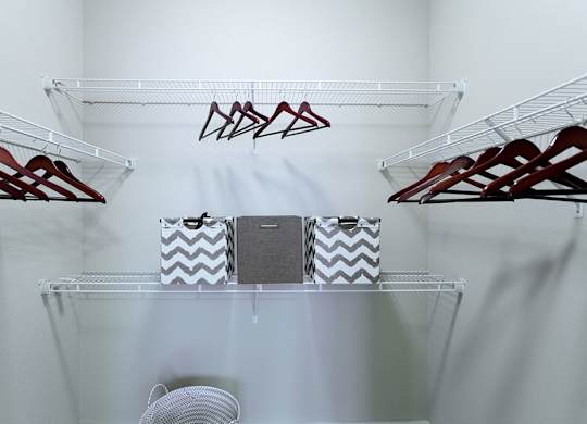 A white closet with clothes hangers and a fan.