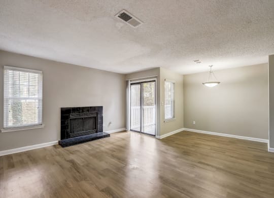 a spacious living room with hardwood floors and black fireplace with glass door to private balcony at Veridian at Sandy Springs apartments