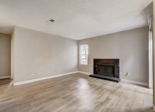 a spacious living room with pet-friendly hardwood floors and black fireplace and natural light at Veridian at Sandy Springs