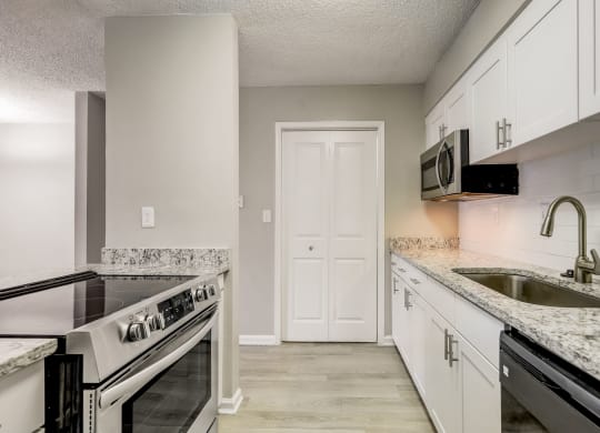 a renovated white kitchen with white cabinets and granite counter tops and a sink at Veridian at Sandy Springs