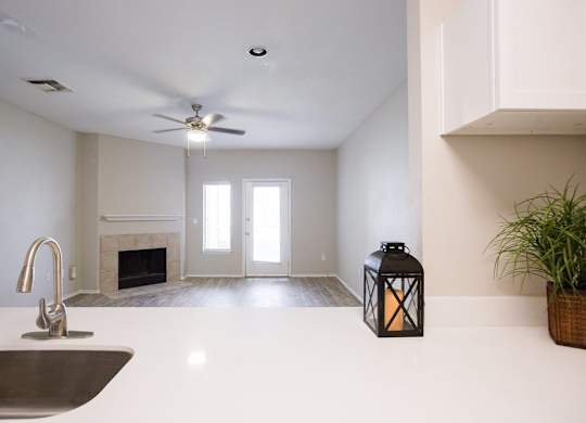 A modern kitchen with a white countertop and a stainless steel sink.