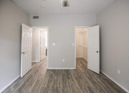 A room with white doors and wood flooring.