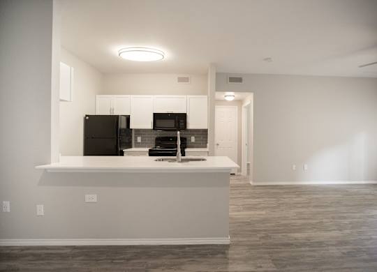 A kitchen with a black refrigerator, microwave, and oven.