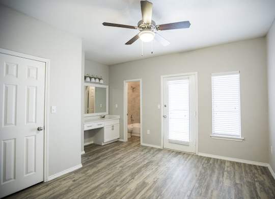 A room with a ceiling fan and a wooden floor.