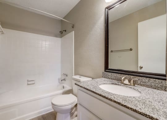 a light colored bathroom with sink and toilet and shower with white tub at Veridian at Sandy Springs