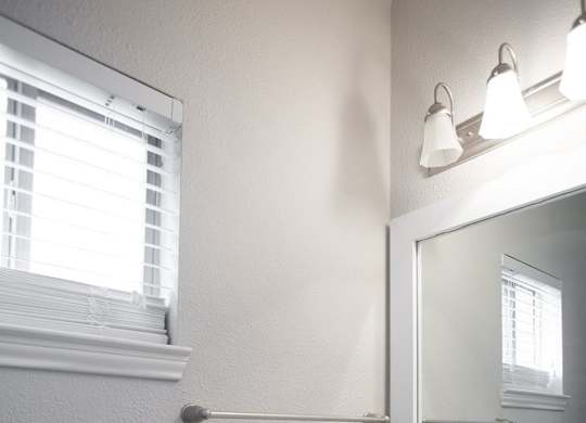 A white sink in a bathroom with a mirror and a window.