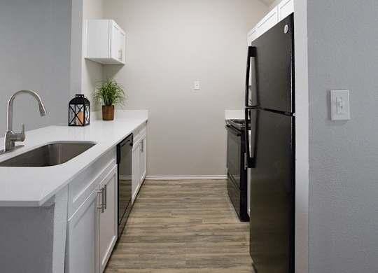 A kitchen with a black fridge and a white sink.