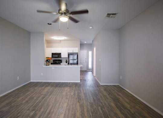 A room with a ceiling fan and wooden flooring.