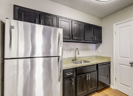 a kitchen with black cabinets and a stainless steel refrigerator at Veridian at Sandy Springs