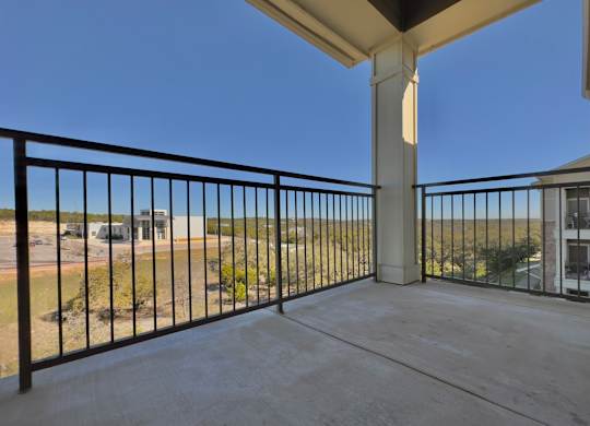 A balcony with a black railing and a concrete floor.