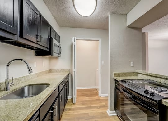 a kitchen with black cabinets and door into a laundry room at Veridian at Sandy Springs