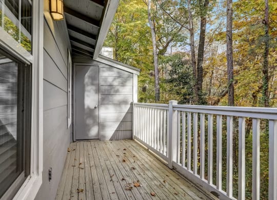a deck with a view of the woods and a door to a storage closet at Veridian at Sandy Springs
