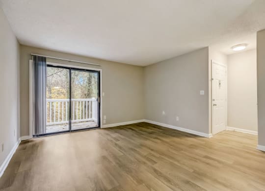 an empty living room with a sliding glass door to a balcony