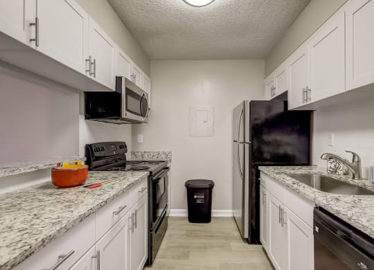 a kitchen with granite counter tops and a stainless steel refrigerator