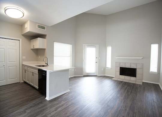 A large, empty room with a fireplace and wooden floors.