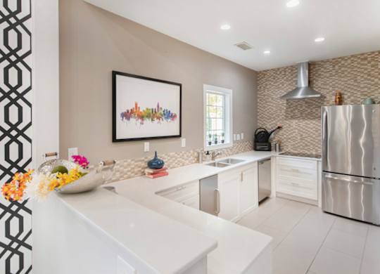A modern kitchen with a white countertop and a fridge on the right.