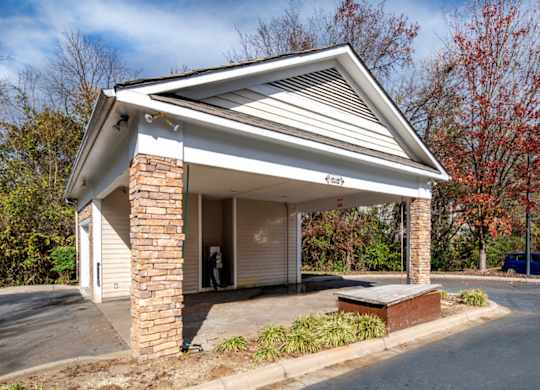A small white building with a gabled roof and a brick pillar.