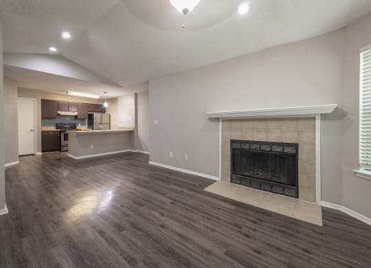 Duluth, GA Apartments with In-Unit Washer and Dryer - The Eclipse - Unfurnished Living Room with Designer Wood Look Plank Flooring, a Fireplace, Ceiling Fan, Window, Near an Open-Concept Kitchen Layout
