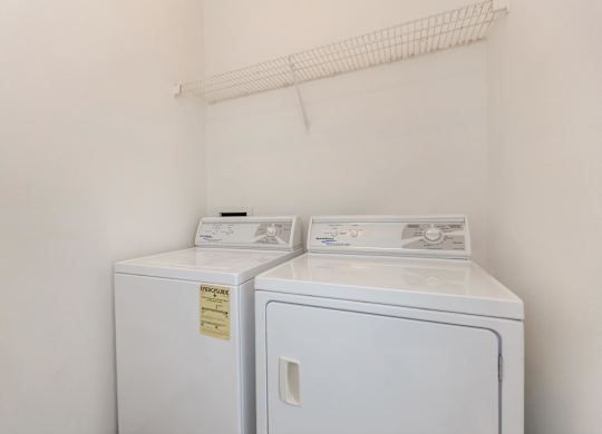 Two white washing machines in a small laundry room.