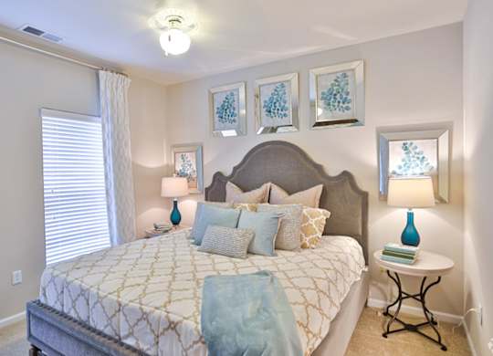 A bedroom with a large bed and a small table with a lamp on it.