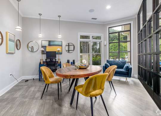 A modern dining room with a round table and yellow chairs.