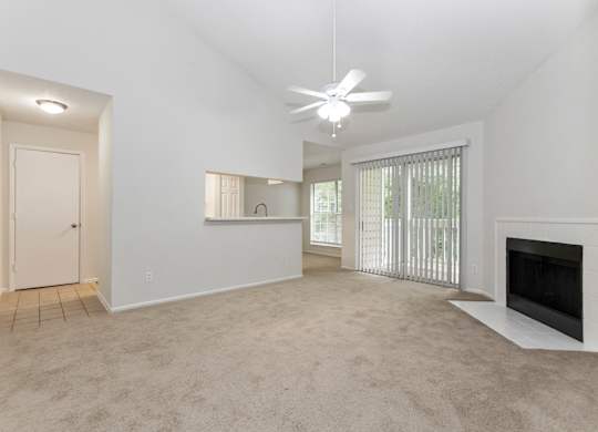 a living room with a fireplace and a ceiling fan at Canopy at Baybrook apartments in Charlotte NC