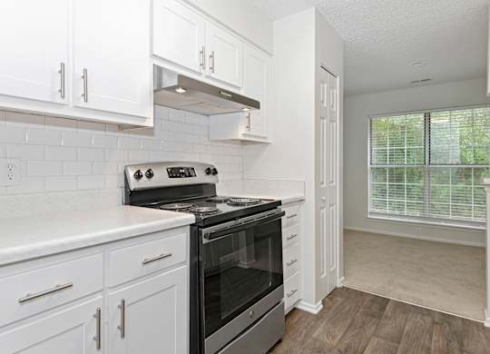 a kitchen with white cabinets and a stainless steel black stove top oven at Canopy at Baybrook apartments in Charlotte NC