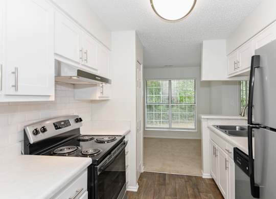 a kitchen with white cabinets and black stainless steel appliances at Canopy at Baybrook apartments in Charlotte NC