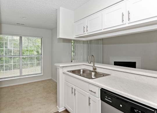 a kitchen with white cabinets and a large window at Canopy at Baybrook apartments in Charlotte NC