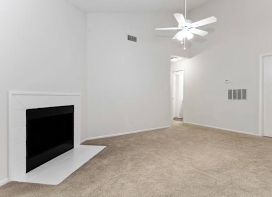 a living room with a fireplace and a vaulted ceiling and fan at Canopy at Baybrook apartments in Charlotte NC