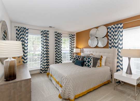 a bedroom with a large bed and a dresser with a lamp on it at Canopy apartments in South Charlotte