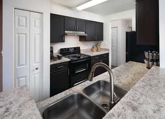 A kitchen with granite countertops and black cabinets.