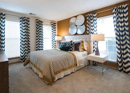 A bedroom with a large bed and a chair.