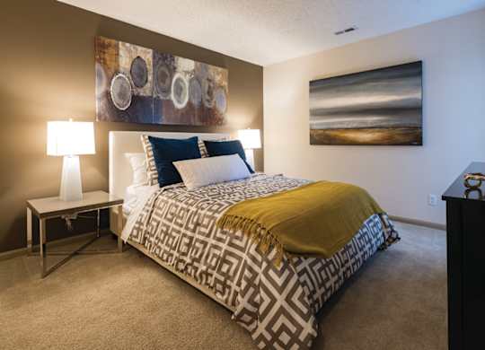 A bedroom with a bed, nightstand, and a painting on the wall.