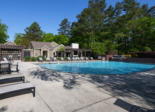 Wynnwood Vinings resident pool with lounge chairs and view of outdoor TV lounge with couches